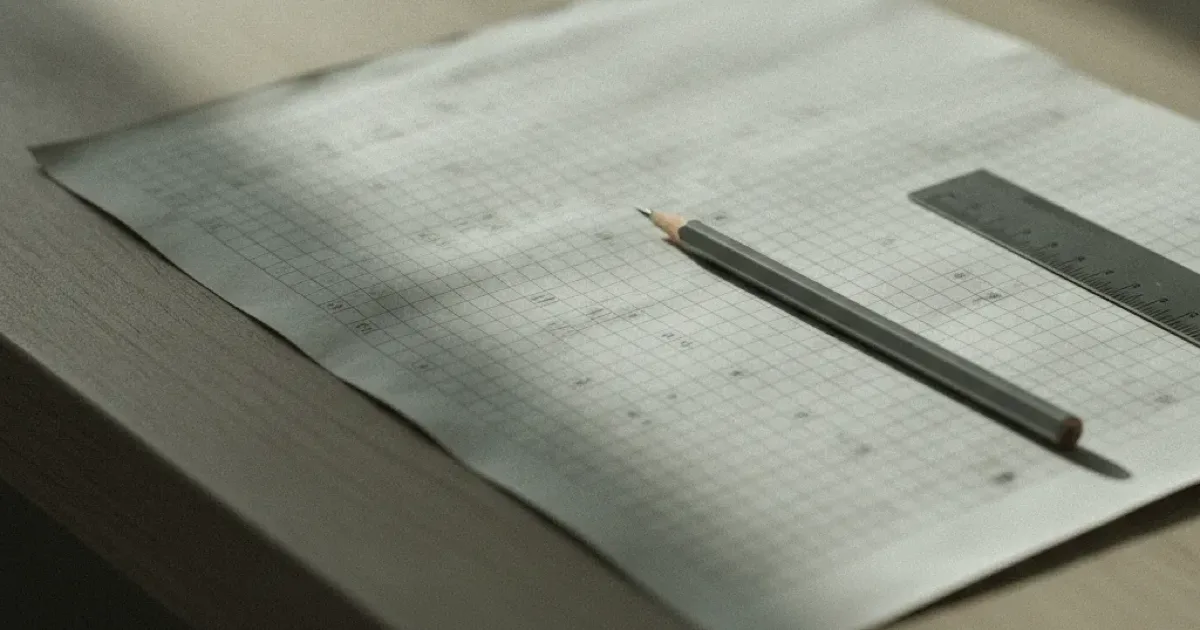 Feuille quadrillée couverte de colonnes de chiffres, crayon et règle métallique posés dessus